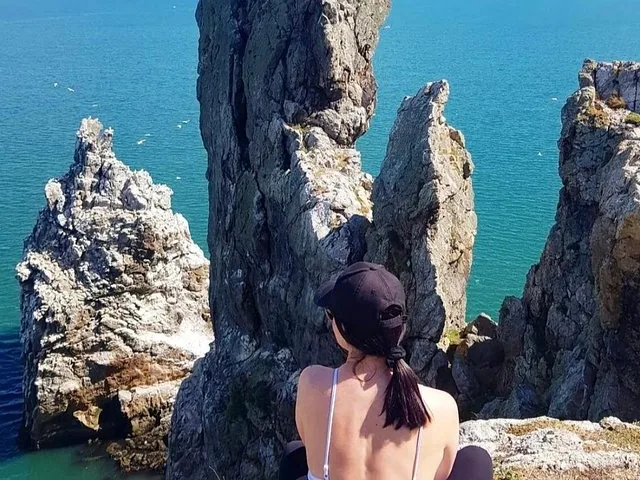 Woman sitting on a cliff overlooking the sea and sea stacks